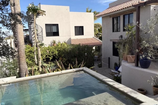 Courtyard with rectangular pool, modern white and stucco buildings, terracotta tile roof, and potted plants